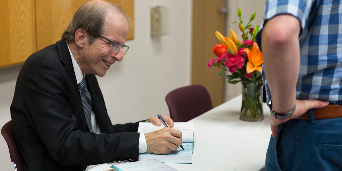 Photo of Michael Krasny signing his book for a fan